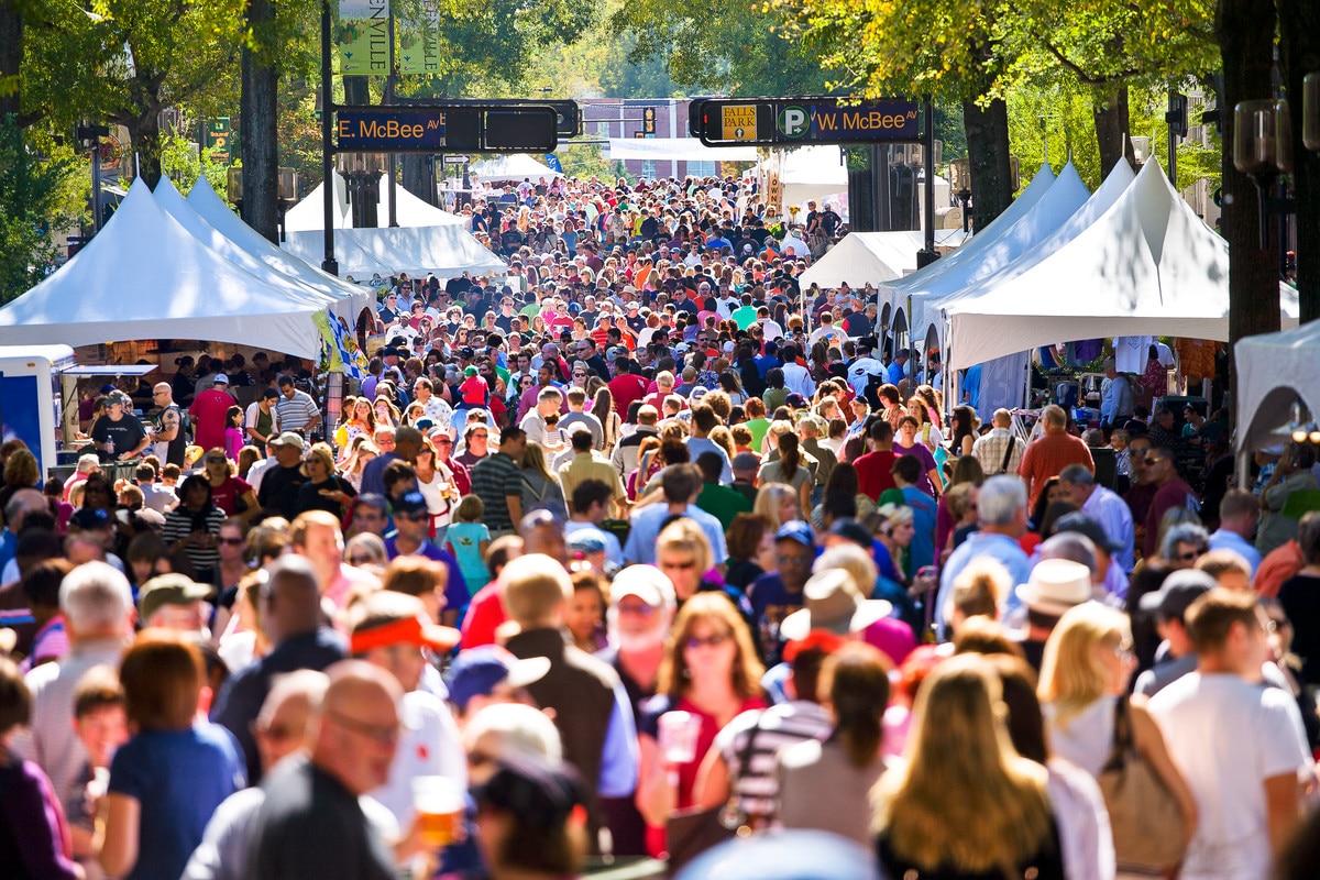 Crowded street festival with white vendor tents and a dense crowd strolling between booths. 20171101fallfest01 - Oliver Law Office