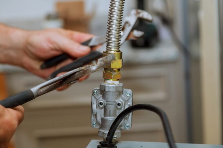 Close-up of hands tightening a brass nut on a metal valve attached to a flexible gas line under a sink during plumbing work Symptoms-Signs-Gas-Leak-Gas-Lines-Photo-768x512 - Oliver Law Office
